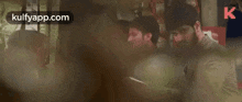 a group of men are standing next to each other in a room and looking at something .