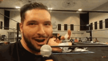 a man in a wrestling ring is holding a microphone and smiling