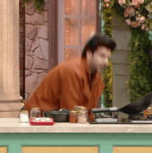 a man in a brown jacket is cooking on a counter