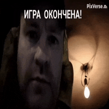 a man in a dark room with a light bulb hanging from the ceiling and the words " игра окончена " on the bottom