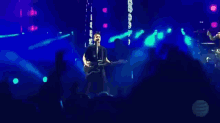 a man playing a guitar and singing into a microphone on stage