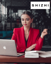 a woman in a red jacket sits at a desk with a laptop and a shizhi logo above her
