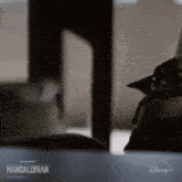 a baby yoda from star wars the mandalorian is sitting on a table in a dark room .