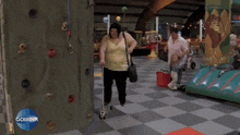 a woman in a yellow tank top is walking in a room with a game21 logo