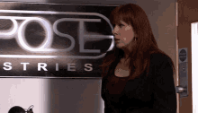 a woman is standing in front of a sign that says pose industries