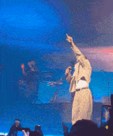 a man in a suit is standing on a stage pointing at the crowd