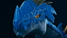 a close up of a blue dragon 's face with a yellow eye