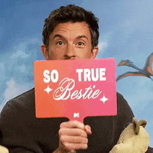 a man holds a sign that says so true bestie