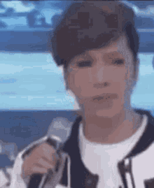 a close up of a person holding a microphone in front of a blue background .