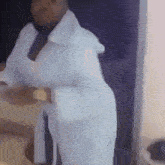 a woman in a white robe is standing in a room holding a cup of coffee .