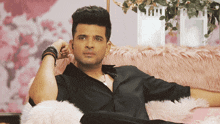 a man in a black shirt is sitting on a pink fur couch