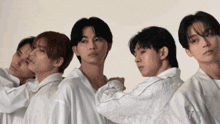 a group of young men are standing in a row and one of them is wearing a white shirt with chinese writing on it