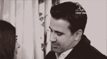 a black and white photo of a man and woman looking at each other .