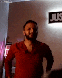 a man with a beard is standing in front of a sign that says jus