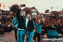 a group of people taking a selfie in front of a crowd with makeagif.com written on the bottom