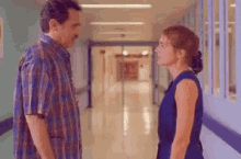 a man and a woman are standing in a hallway and looking at each other