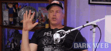 a man wearing a black shirt that says pel on it is talking into a microphone