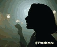 a silhouette of a woman smoking a cigarette in a dark room