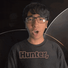 a man wearing glasses and a black shirt that says hunter on it