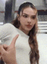 a woman in a white shirt is giving a thumbs up