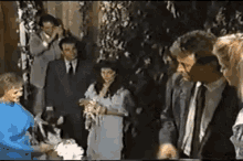 a group of people standing around a bride and groom at a wedding
