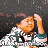 a young boy is making a funny face while holding his hand to his head .