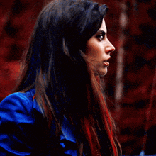 a woman with long red hair and blue eyes looks up