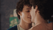 two young men are kissing each other in front of a green sign