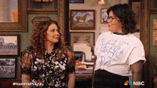 two women are standing next to each other in a room with nbc written on the bottom right