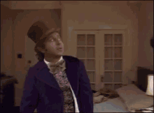 a man in a purple jacket and bow tie is standing in a bedroom holding a sword .