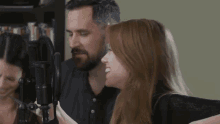 a man and a woman are singing into microphones in front of a bookshelf