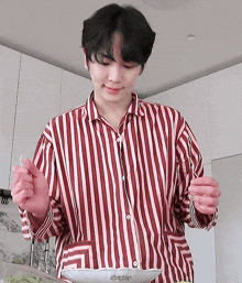 a man wearing a red and white striped shirt is holding a fork and a bowl of food