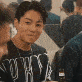 a young man with a piercing in his lip is sitting at a table with a bottle of beer in front of him .