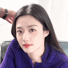 a close up of a woman wearing a purple sweater with a watch on her arm