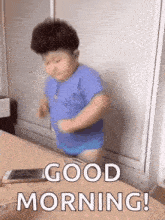 a little boy in a blue shirt is standing on a bed and says `` good morning '' .