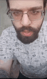 a man with glasses and a beard is wearing a t-shirt with skulls on it