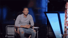 a man is sitting in a director 's chair on the voice