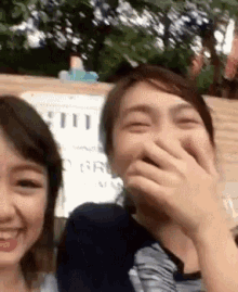 a man and a woman are laughing together while covering their mouths .