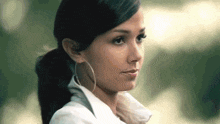 a woman wearing hoop earrings and a white shirt looks to the side