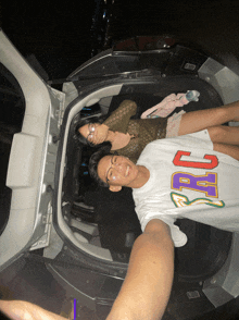 a man and a woman are laying in the back of a car with the man wearing a shirt that says arg