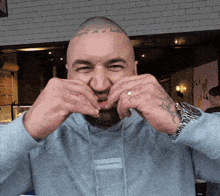 a man with a tattoo on his head is making a face with his hands