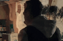 a man in a hoodie stands in front of a window in a room