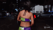 a woman in a green top is walking down a street in front of a trailer that says #raw on it