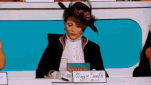 a woman in a hat sits at a desk with a sign that says snatch maggie smith