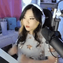 a woman wearing headphones and a cat ear headband is sitting in front of a microphone .