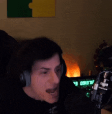 a man is wearing headphones and screaming into a microphone .