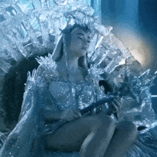 a woman in a costume made of ice is sitting on a bed