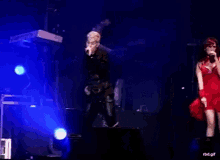 a man singing into a microphone next to a woman in a red dress with rbd.gif at the bottom