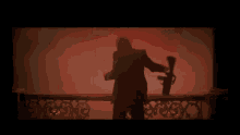 a man in a black suit is standing on a balcony in a dark room