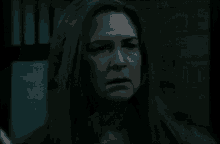 a woman with long hair is standing in a dark room .